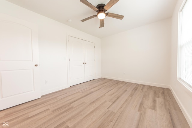 unfurnished bedroom with baseboards, a closet, a ceiling fan, and light wood-style floors
