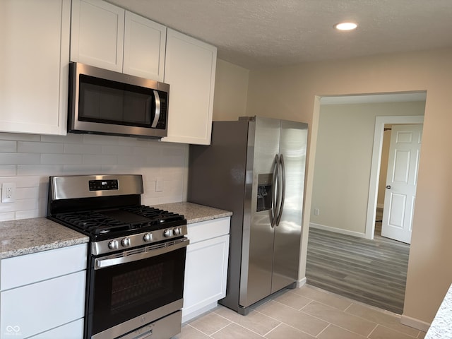 kitchen with white cabinets, stainless steel appliances, and tasteful backsplash