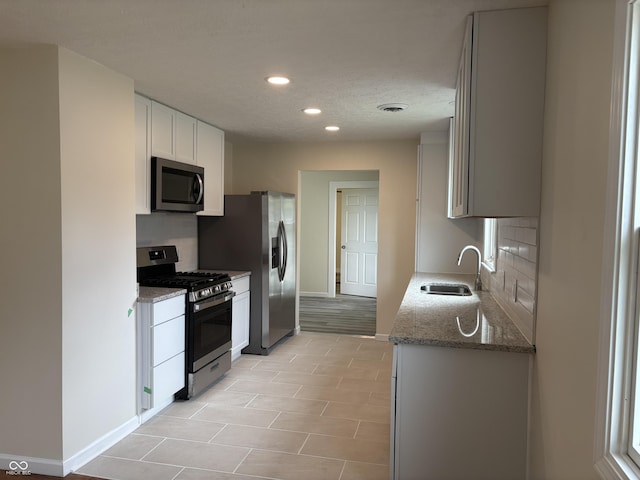 kitchen featuring backsplash, appliances with stainless steel finishes, a sink, baseboards, and recessed lighting