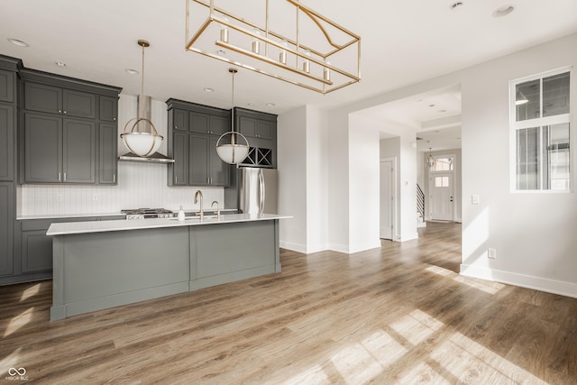 401 Jersey St, Westfield, IN 46074 - kitchen featuring light countertops, an island with sink, light wood-style flooring, freestanding refrigerator, and backsplash