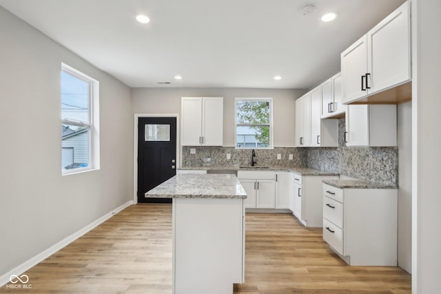 202 Mckim Ave, Indianapolis, IN 46201 - kitchen with decorative backsplash, a kitchen island, light stone counters, and light wood-type flooring