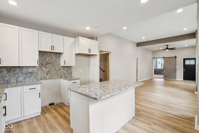 202 Mckim Ave, Indianapolis, IN 46201 - kitchen with light wood-style floors, a barn door, light stone countertops, and backsplash