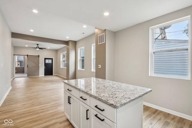 202 Mckim Ave, Indianapolis, IN 46201 - kitchen with light wood-style flooring, a barn door, a center island, baseboards, and visible vents