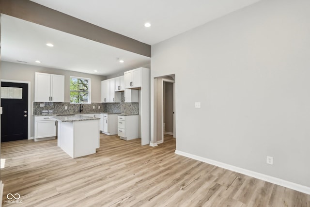202 Mckim Ave, Indianapolis, IN 46201 - kitchen featuring light wood-style flooring, baseboards, white cabinetry, decorative backsplash, and a kitchen island