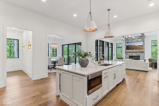 11064 Hamilton Run, Zionsville, IN 46077 - kitchen featuring a sink, stainless steel microwave, a chandelier, white cabinetry, and light wood finished floors