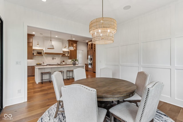 11064 Hamilton Run, Zionsville, IN 46077 - dining space with a decorative wall, wood finished floors, a chandelier, and recessed lighting