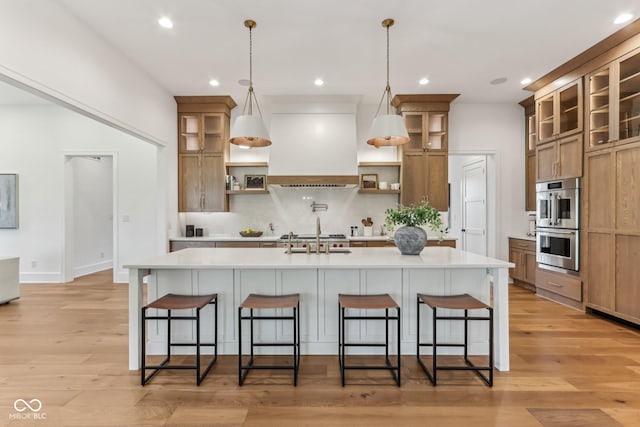 11064 Hamilton Run, Zionsville, IN 46077 - kitchen with open shelves, custom range hood, light countertops, a breakfast bar, and a center island with sink