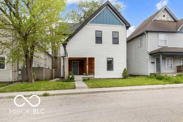 traditional home with board and batten siding, fence, and a front lawn