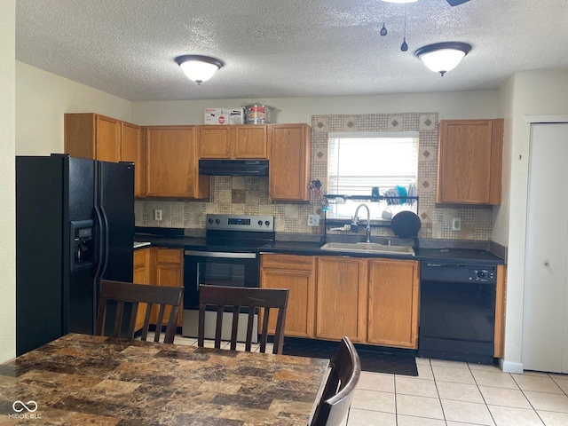 2350 Harvest Moon Dr, Greenwood, IN 46143 - kitchen with dark countertops, under cabinet range hood, tasteful backsplash, a sink, and black appliances
