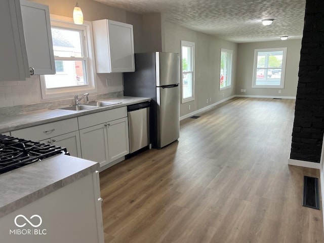 kitchen with white cabinetry, decorative backsplash, stainless steel appliances, and light wood-style floors