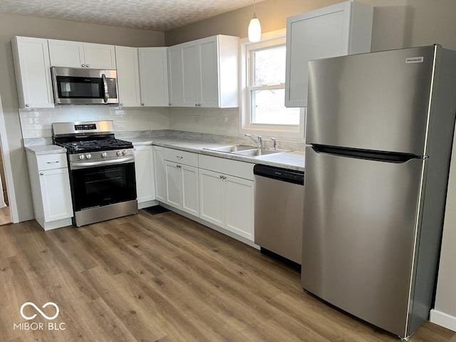 kitchen featuring a sink, stainless steel appliances, tasteful backsplash, light countertops, and white cabinets