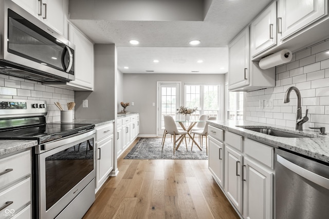 2823 Somerset Bay, Indianapolis, IN 46240 - kitchen with appliances with stainless steel finishes, white cabinets, light wood-style flooring, recessed lighting, and a textured ceiling