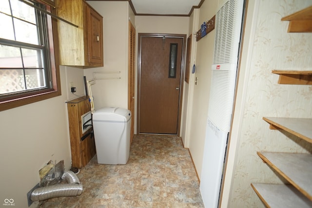 clothes washing area featuring stone finish floor, ornamental molding, cabinet space, and a heating unit