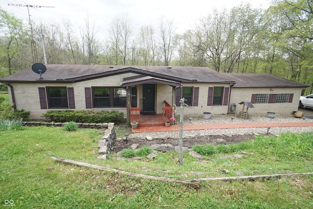 view of front of home with roof with shingles, a front yard, and brick siding