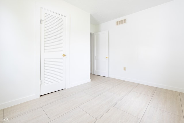 unfurnished bedroom featuring baseboards, a closet, light wood finished floors, and visible vents