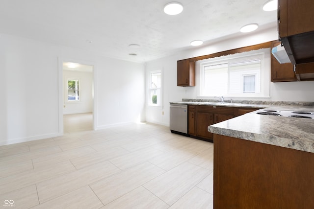 kitchen with light countertops, baseboards, stainless steel dishwasher, under cabinet range hood, and stovetop