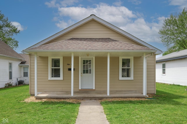 bungalow-style house featuring a front lawn, roof with shingles, central AC, and covered porch
