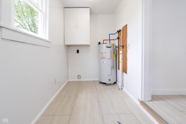 laundry room featuring baseboards, electric dryer hookup, cabinet space, and electric water heater