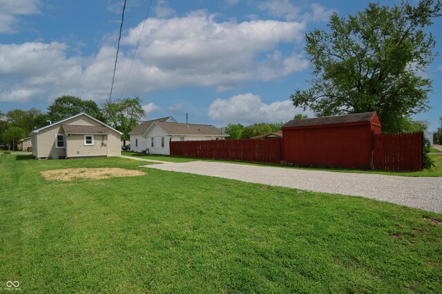 view of yard with fence and gravel driveway
