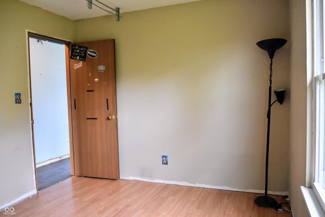 spare room with baseboards and wood finished floors
