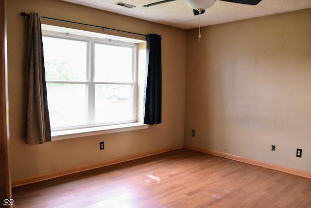 empty room featuring ceiling fan, visible vents, baseboards, and light wood-type flooring