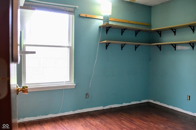 spare room with baseboards, dark wood-style flooring, and a wealth of natural light
