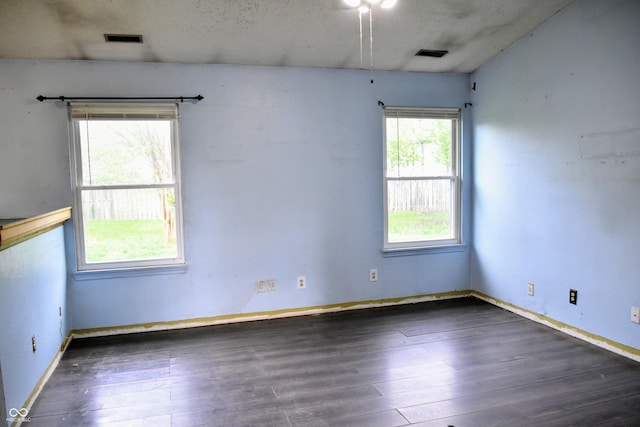 spare room featuring baseboards, wood finished floors, and visible vents