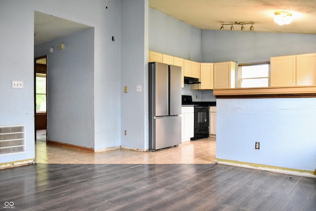 kitchen with visible vents, freestanding refrigerator, under cabinet range hood, black range with electric cooktop, and cream cabinetry