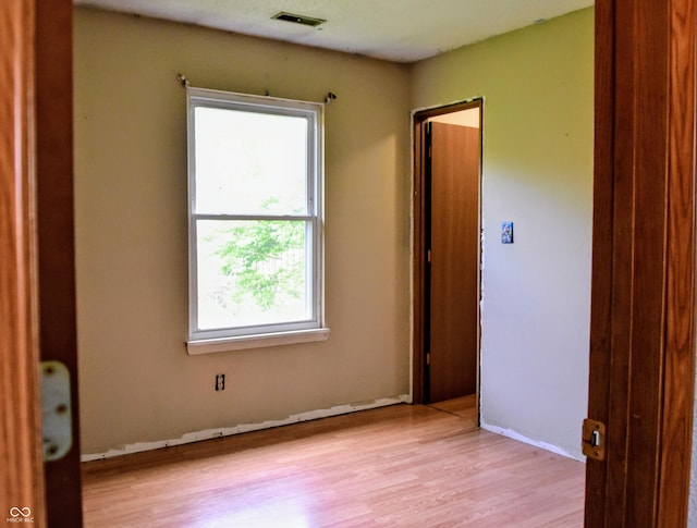 unfurnished room featuring visible vents, light wood-style floors, baseboards, and a wealth of natural light
