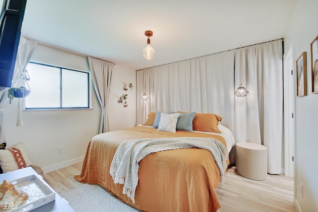 bedroom featuring light wood finished floors and baseboards