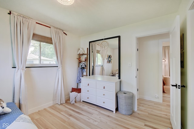 bedroom with light wood-type flooring, multiple windows, and baseboards