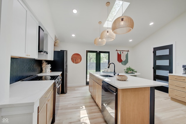 kitchen featuring dishwasher, stainless steel electric range oven, a sink, a skylight, and backsplash