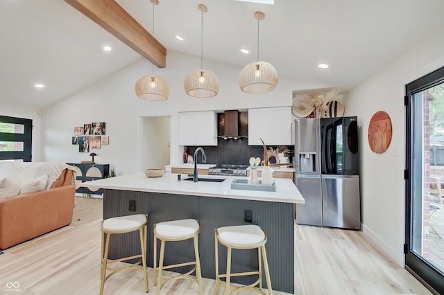 kitchen with stainless steel fridge, a sink, wall chimney exhaust hood, light wood-style flooring, and tasteful backsplash