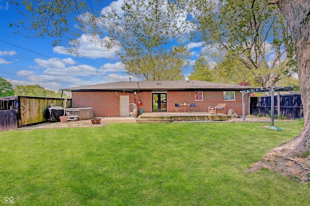 rear view of property with a hot tub, a wooden deck, and brick siding