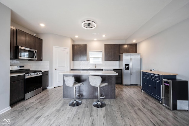 2628 Lamar Dr, Whitestown, IN 46075 - kitchen with stainless steel appliances, a center island, backsplash, a kitchen bar, and light wood-type flooring
