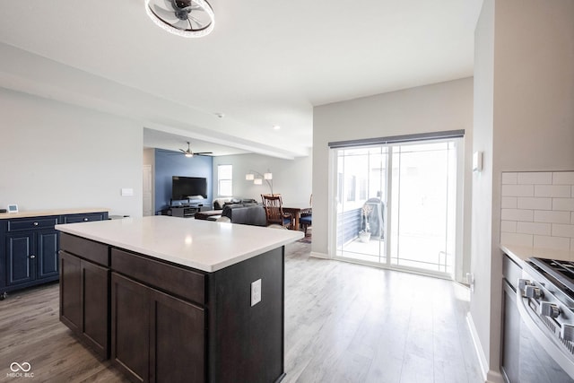 2628 Lamar Dr, Whitestown, IN 46075 - kitchen with stainless steel gas stove, light countertops, light wood finished floors, ceiling fan, and open floor plan
