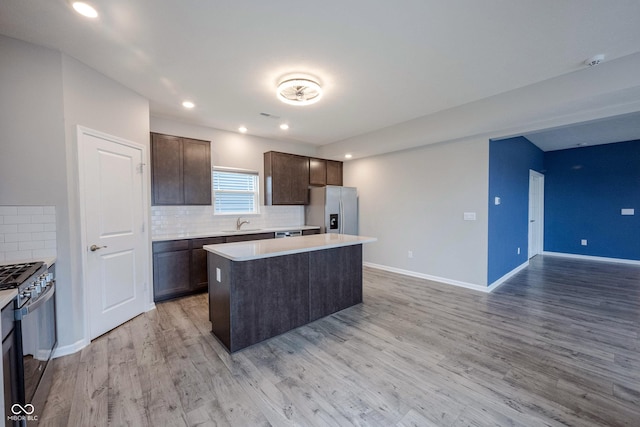 2628 Lamar Dr, Whitestown, IN 46075 - kitchen with stainless steel appliances, dark brown cabinets, a center island, tasteful backsplash, and light countertops