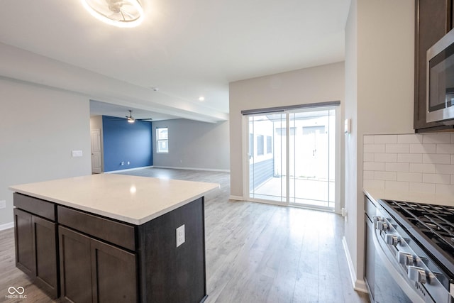 2628 Lamar Dr, Whitestown, IN 46075 - kitchen with stainless steel appliances, light wood-style flooring, decorative backsplash, dark brown cabinets, and a ceiling fan