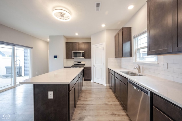2628 Lamar Dr, Whitestown, IN 46075 - kitchen featuring appliances with stainless steel finishes, light wood finished floors, a kitchen island, dark brown cabinets, and tasteful backsplash