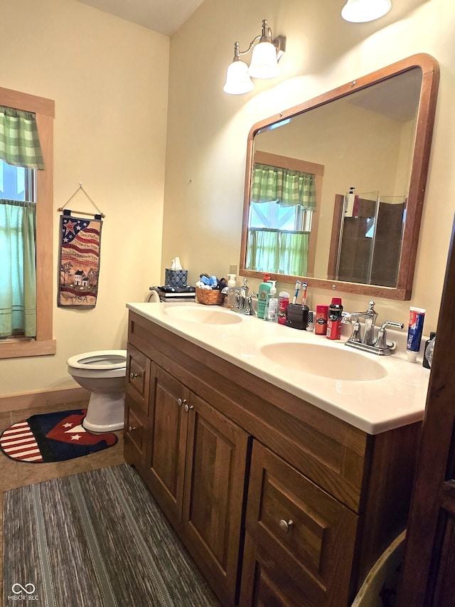 full bathroom featuring toilet, a stall shower, and double vanity