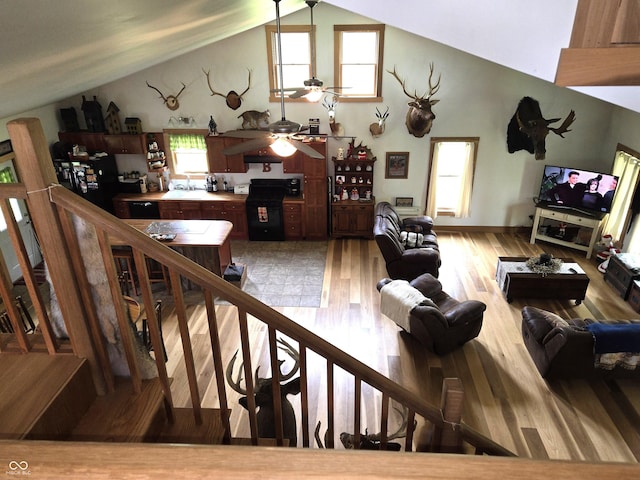 living area featuring ceiling fan, light wood-style floors, and high vaulted ceiling