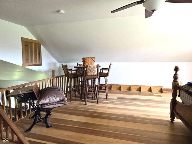 living area with hardwood / wood-style floors, a ceiling fan, and vaulted ceiling