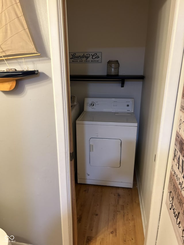 clothes washing area featuring laundry area, washer / dryer, and wood finished floors