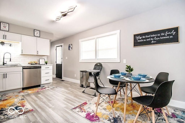 kitchen with baseboards, white cabinetry, tasteful backsplash, a sink, and dishwasher
