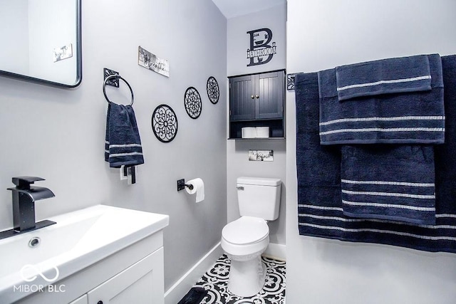 half bathroom featuring toilet, baseboards, and vanity