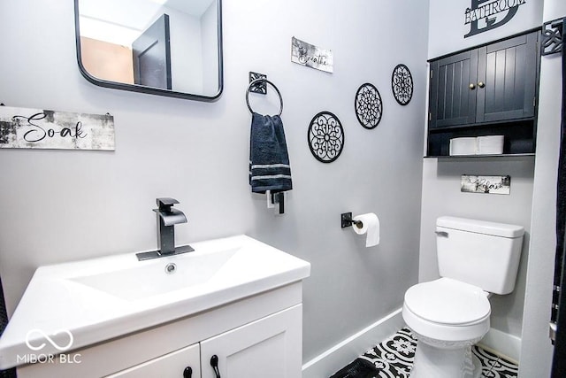 bathroom with baseboards, toilet, and vanity