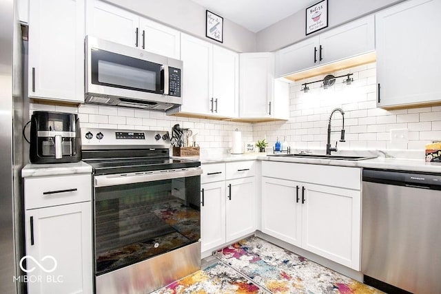 kitchen with backsplash, white cabinetry, appliances with stainless steel finishes, and a sink