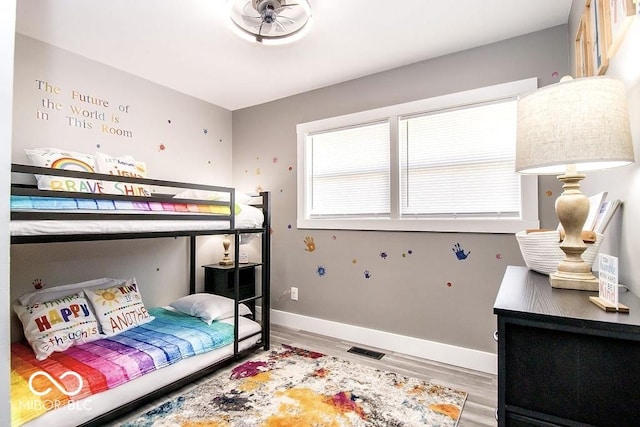 bedroom with baseboards, visible vents, and wood finished floors