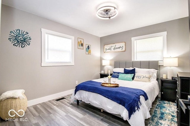 bedroom featuring baseboards, wood finished floors, and visible vents