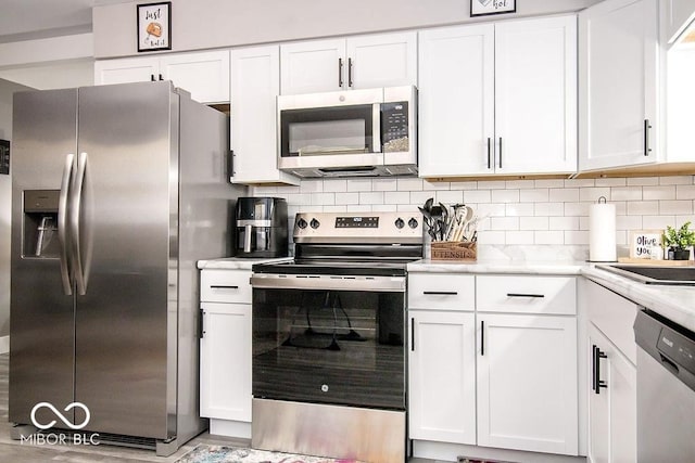kitchen featuring light countertops, tasteful backsplash, white cabinets, and stainless steel appliances